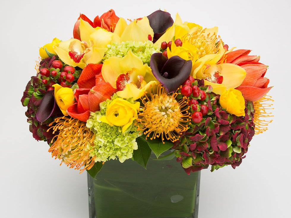 Fall flower arrangements NYC: Harvest Bounty by Jerome Florists, with yellow cymbidium orchids, calla lilies, amaryllis and burgundy hydrangea in a leaf-lined glass cube