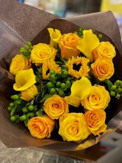 Erly Sunset: yellow and orange roses, yellow calla lilies, small sunflowers and green hypericum berries in brown kraft paper