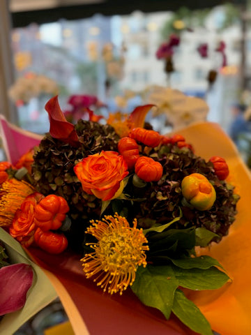 PumpKing close-up of an orange rose, mini pumpkins, orange pincushion protea and dark antique hydrangea