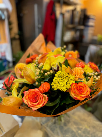 Fall in Love front view: orange roses, dahlias, yellow callas and a yellow cymbidium orchid with mini pumpkins, orange wrap