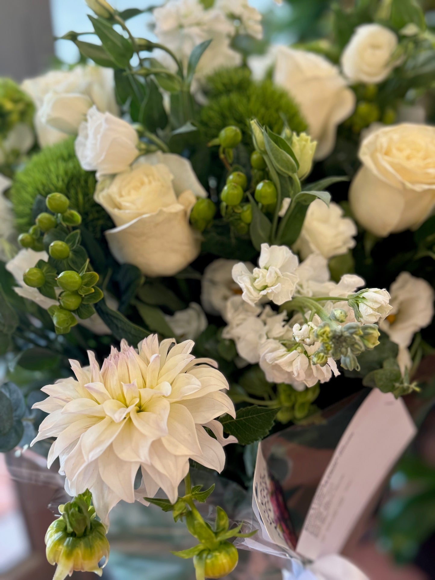 Erly Afternoon with a large white dahlia, cream roses, white stock and green dianthus, a card tucked in the wrap