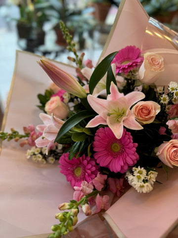 Pink Passion side view with pink lilies, hot pink gerberas, peach roses and white daisies in blush paper