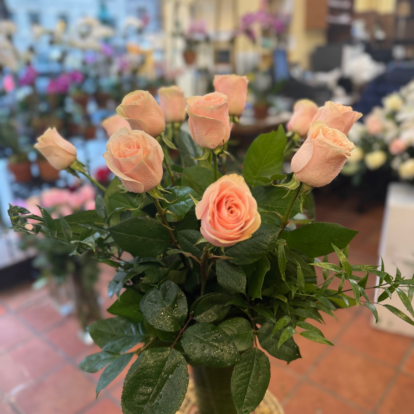 Pink Roses, peach-pink roses with glossy greenery in a tall leaf-lined glass vase on a gold stand
