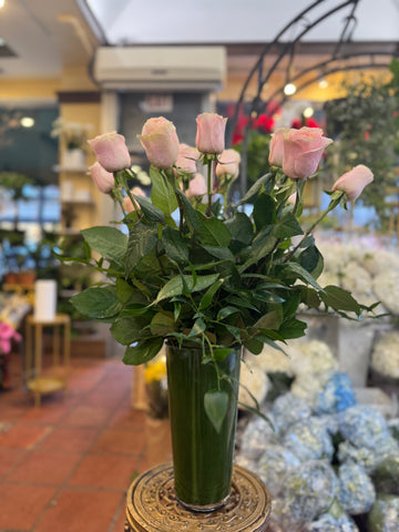 Pink Roses, light pink long-stem roses with greenery in a tall leaf-lined glass vase in the shop