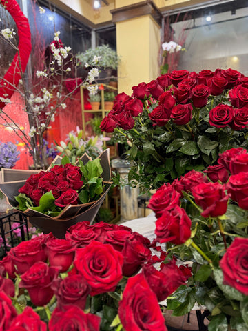 Complete Love, portrait view of a wrapped red rose bouquet and red rose arrangements with scattered petals