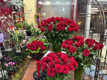 Complete Love, wide view of the red rose arrangements in leaf-lined vases and the wrapped bouquet with red ribbon