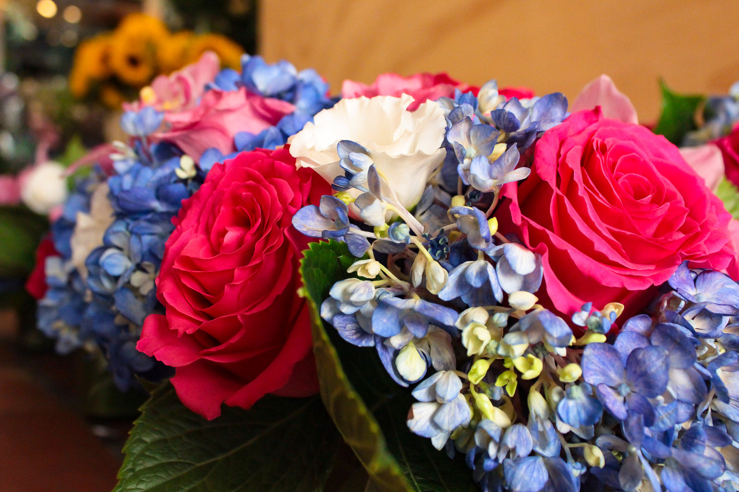 Jerome's - Spoil me sample close-up: red and hot pink roses with blue hydrangea and white lisianthus
