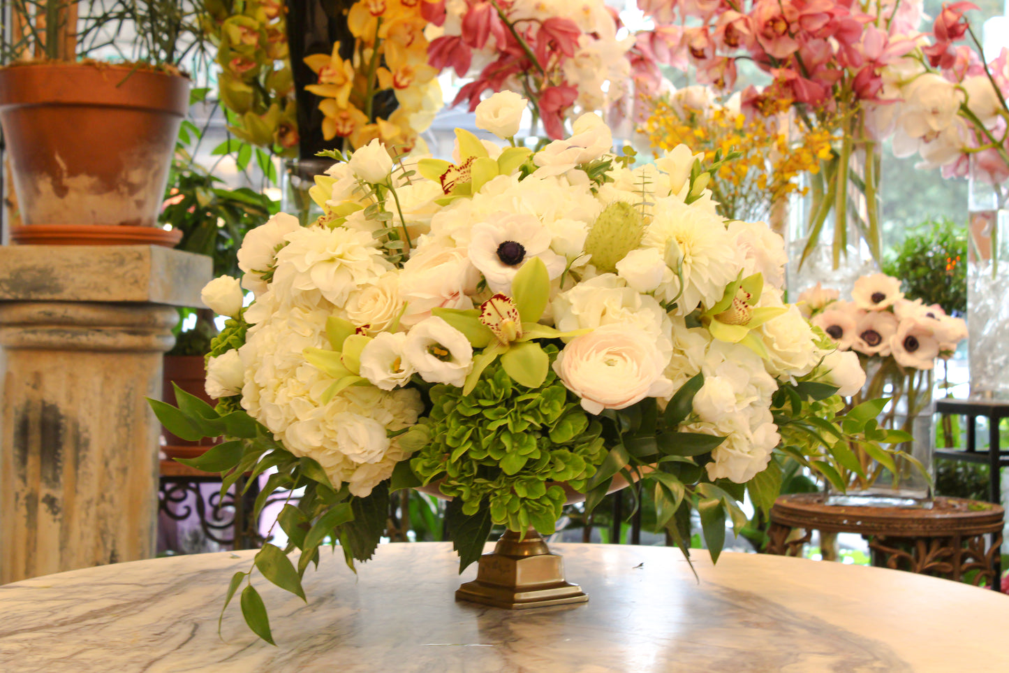 Golden Valentina on a marble table: white roses, white anemones, white and green hydrangea and green orchids in a gold bowl