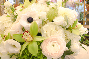 Golden Valentina close-up: green cymbidium orchid, pale blush ranunculus, white anemone, white roses and green hydrangea