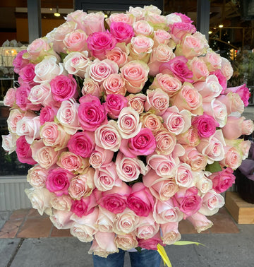 Mother of all Bouquets, a huge round bouquet of hot pink, blush and cream roses, held outside the shop