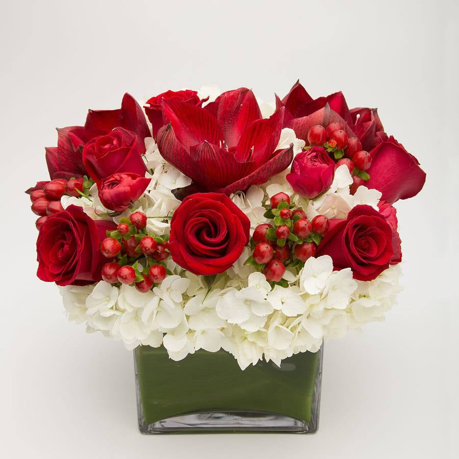 Floral arrangement with red roses, white hydrangeas, and red berries in a clear vase – Jerome Florists NYC