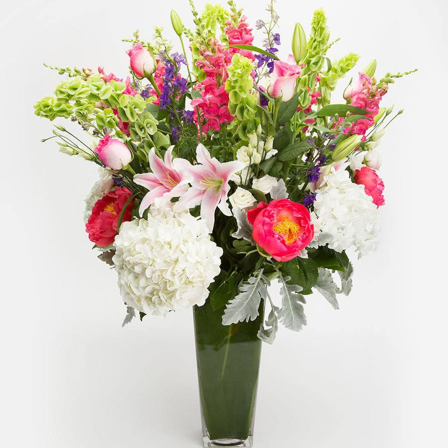 Spring Time, pink lilies, coral peonies, white hydrangea, pink roses, snapdragons and bells of Ireland in a tall vase
