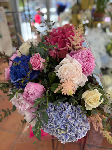 
                    
                      Punch H close view of raspberry hydrangea, pink and blush peonies, a cream rose, peach astilbe and blue hydrangea
                    
                  