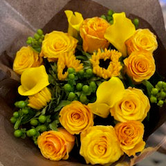 Erly Sunset: yellow and orange roses, yellow calla lilies, small sunflowers and green hypericum berries in brown kraft paper