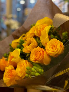 
                    
                      Erly Sunset side view of yellow roses, yellow callas and sunflowers with green hypericum berries in kraft wrap
                    
                  