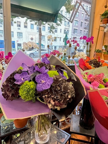 
                    
                      Dark Love from the front: purple vanda orchids over dark antique hydrangea and green dianthus, in a glass vase
                    
                  