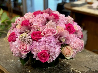
                    
                      Jab, medium size: pink hydrangea dome with hot pink and blush roses, pink cymbidium orchids and white hyacinth in a low vase
                    
                  