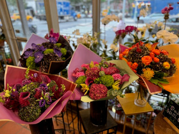 
                    
                      Shop window bouquets in vases: Dark Love (back left), Green Envy (front left), pink Hy Love and PumpKing (right)
                    
                  