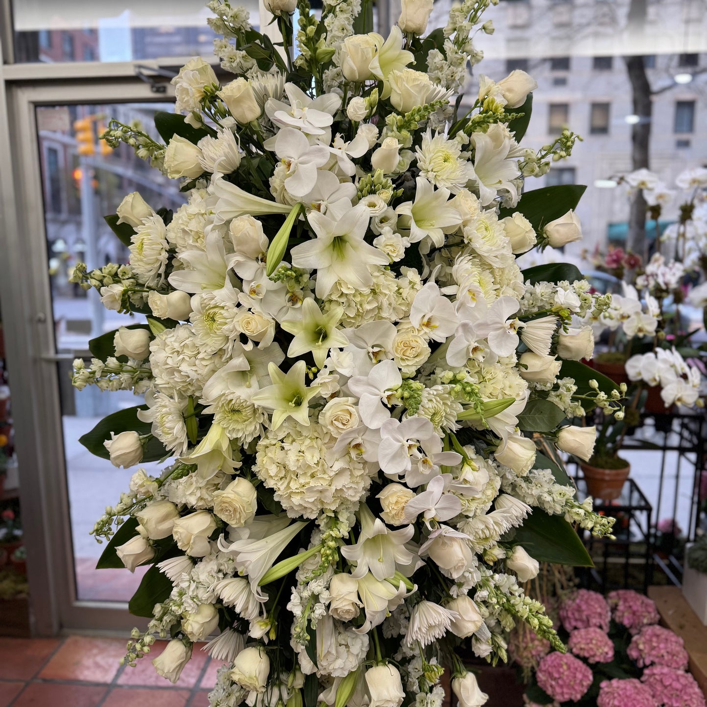 Eternal Rest large size, all-white standing spray of roses, lilies, hydrangea and stock on an easel in the shop