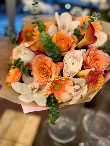 
                    
                      Erly Riser: orange roses, orange gerberas, cream ranunculus, white cymbidium orchids and red-orange callas in kraft paper
                    
                  