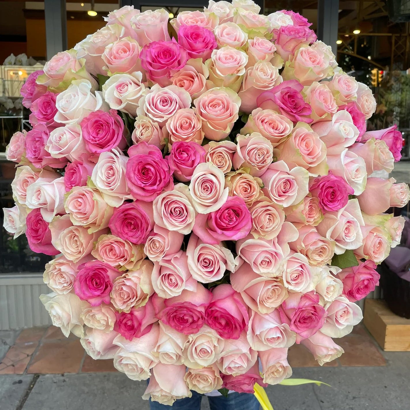 Mother of all Bouquets, a huge round bouquet of hot pink, blush and cream roses, held outside the shop