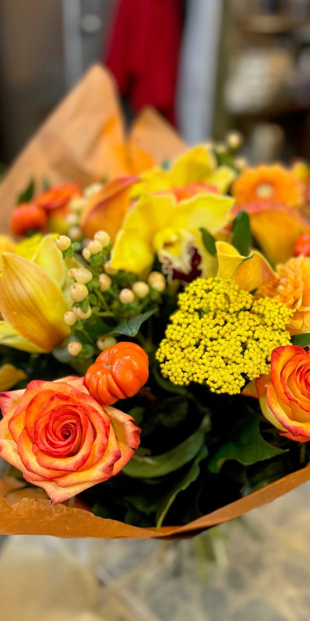 Fall in Love autumn bouquet of orange roses, dahlias, yellow calla lilies, cymbidium orchids and hypericum berries, wrapped in orange paper at Jerome Florists